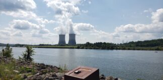 Zaporijya Nükleer Güç Santralı’nda Soğutma Sistemi Yangını: Taraflar Birbirini Suçluyor a body of water with a group of smokestacks in the distance