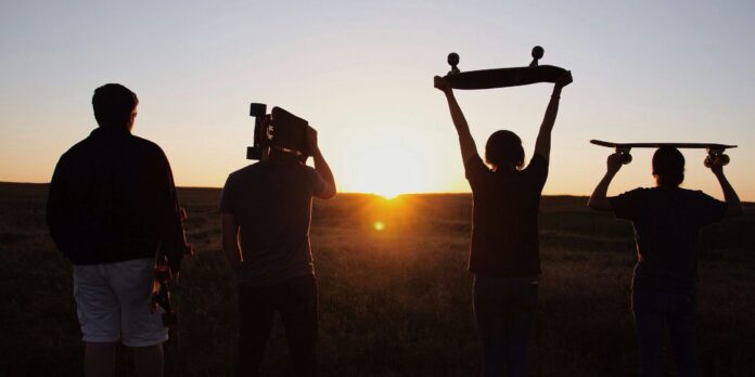 group of people holding skateboards under sunset