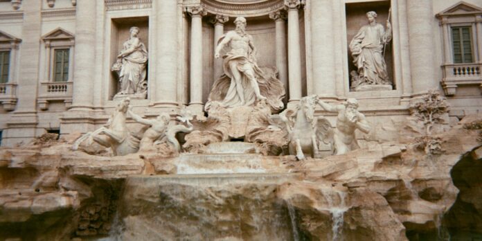 a fountain in front of a building with statues on it
